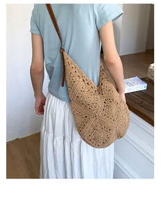Detailed close-up of a hollow woven straw tote bag with brown faux leather strap
