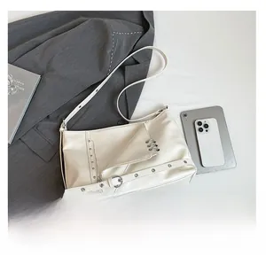 Dettaglio di una borsa tote chic color crema stile biker con zip in metallo e fibbie