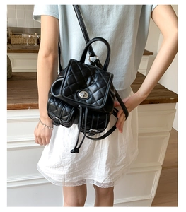 Detail of black quilted leather backpack with turn-lock closure and side buckle pockets