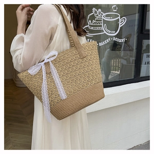 Detail of a beige woven tote bag with white lace bow on a female model outdoors