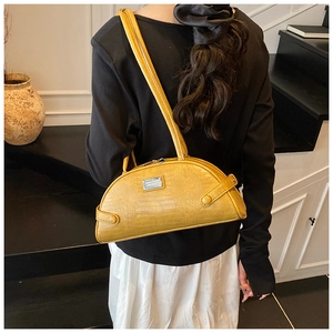 Detail of yellow crocodile pattern handbag with rectangular metal logo plate