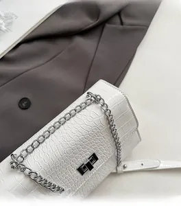 Detail of white crocodile pattern shoulder bag with silver chain strap and metal lock