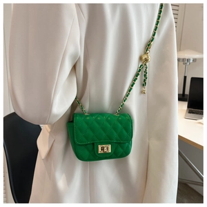 Detail of a mini green quilted saddle bag with golden chain on white blazer
