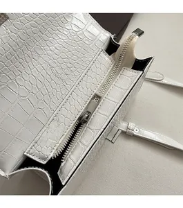 Macro shot of silver metal zipper and crocodile pattern on white leather bag