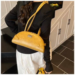 Detail of yellow mustard faux crocodile leather handbag showing texture and silver metal plaque