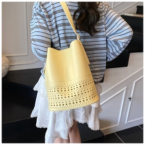 Detail of yellow hollowed-out bucket bag showing laser-cut patterns and fine PU leather texture