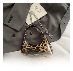 Detail of leopard print handbag with silver metal chain on a grey blazer fabric