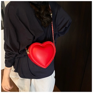 Détail d'un sac cœur rouge en cuir avec bandoulière chaîne dorée et coutures précises