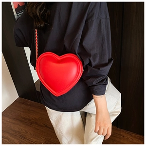 Dettaglio della borsa a tracolla rossa a forma di cuore con catena in metallo sulla modella