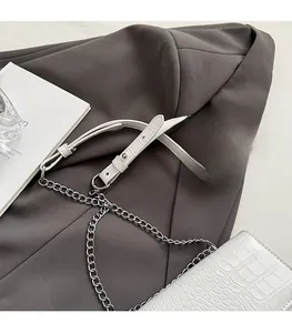 Close-up of white crocodile pattern PU leather with silver metal chain and shoulder strap