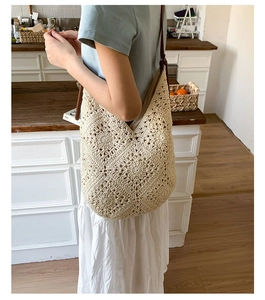 Detail view of beige handmade crochet shoulder bag featuring floral hollow-out weaving