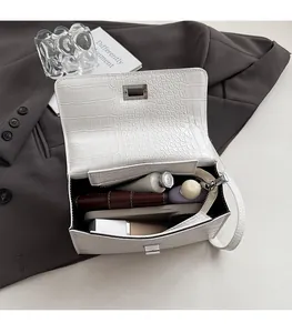 Macro view of white croc-embossed square bag showing internal zipper compartments and capacity