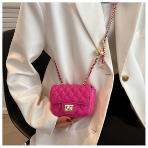 Detail of pink quilted leather mini crossbody bag with gold chain and ball charm on model