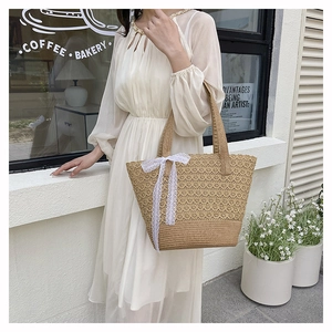 Close-up of a woven straw tote bag featuring a decorative white lace bow detail
