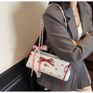 Detail of white bow shoulder bag with red polka dots and heart-shaped metal pendant charm