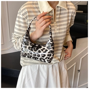Detail view of glossy leopard print hobo bag with dual metal zippers and leather handle
