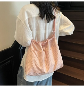 Detail of pink pleated canvas tote bag with drawstring closure and waffle texture