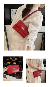 Detail of red crocodile texture crossbody bag with silver clasp and chain strap