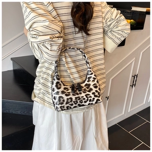 Detail of glossy leopard print handbag with silver chain strap on model shoulder