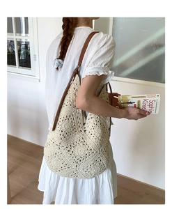 Detail of cream crochet knit tote bag with hollow pattern and brown leather straps