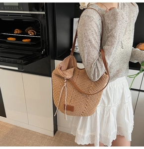 Detail of woven straw tote bag featuring leather shoulder straps and drawstring closure