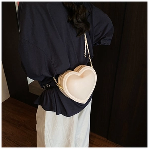 Mannequin portant un sac à bandoulière en forme de cœur crème avec chaîne dorée élégante