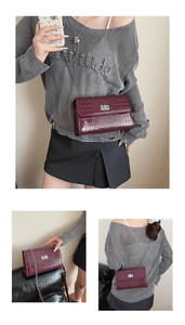 Three-way view of a burgundy crocodile pattern crossbody bag with silver chain and metal lock