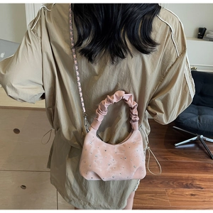 Detail view of light pink crescent bag with sparkling rhinestones and a chain strap