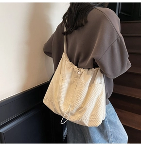 Detail of cream pleated canvas tote showing drawstring closure and quilted texture on model