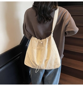 Close-up of cream-colored pleated tote bag showing textured puff fabric and drawstring