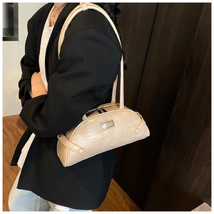 Detail of beige crocodile embossed shoulder bag worn by model in minimalist setting