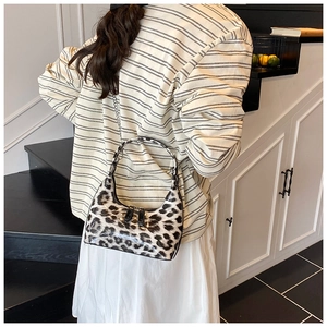 Detail of glossy leopard print crescent bag featuring silver chain and dual zippers