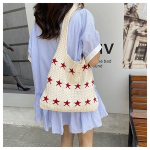 Street style shot of a knitted star tote bag with red star pattern on a cream base