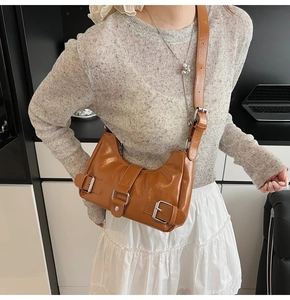 Close-up of caramel brown hobo bag featuring decorative silver buckles and leather straps