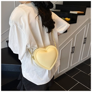 Modella che indossa una borsa a tracolla a forma di cuore giallo chiaro con catena