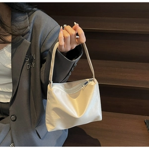 Gros plan d'un sac à bandoulière en cuir crème minimaliste avec fermeture éclair métallique