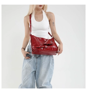 Detail of red patent leather tote with silver metal eyelets and punk style buckles