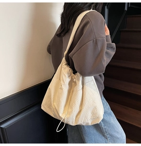 Detail view of large beige tote bag with textured fabric and drawstring closure