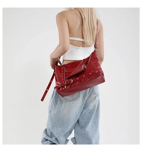 Dettaglio della borsa punk in vernice rossa con borchie e fibbie sulla modella