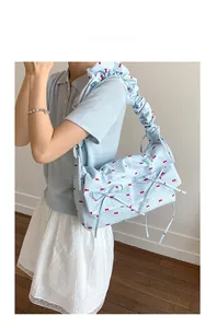 Détail du sac bleu clair à motifs nœuds rouges et bandoulière à volants plissés