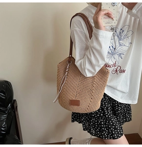 Detail of woven straw tote bag with brown leather logo patch and artisan V-shape pattern