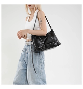 Dettaglio della borsa punk in pelle verniciata nera con rivetti argentati e spille da balia