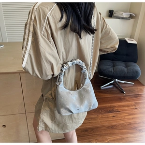 Silver pleated dumpling bag with rhinestones and chain strap shown on a model