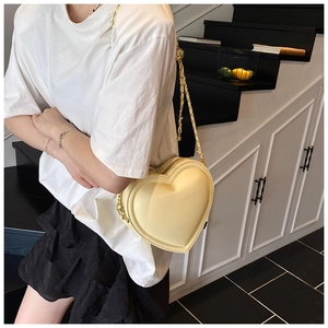 Modella che indossa una borsa a tracolla a cuore giallo crema con catena dorata