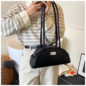 Detailed view of a black crocodile pattern baguette shoulder bag held by a model