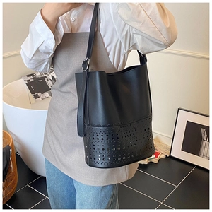 Close-up of black hollow-out bucket bag with laser-cut patterns and adjustable strap