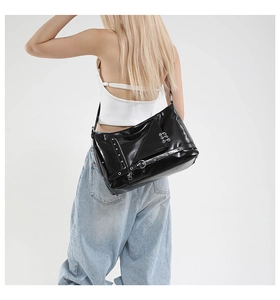 Détail du sac punk en cuir verni noir avec œillets métalliques et épingles de sûreté