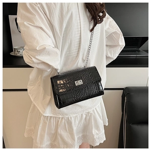 Close-up of black crocodile pattern crossbody bag with silver chain and metal lock