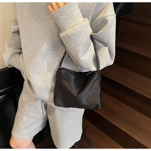 Sac sous le bras chic en nylon noir au fini satiné porté sur l'épaule du mannequin