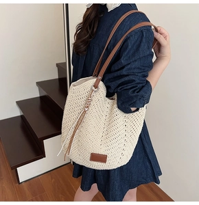 Detail of hand-woven beige tote bag with slim brown leather strap and boho texture